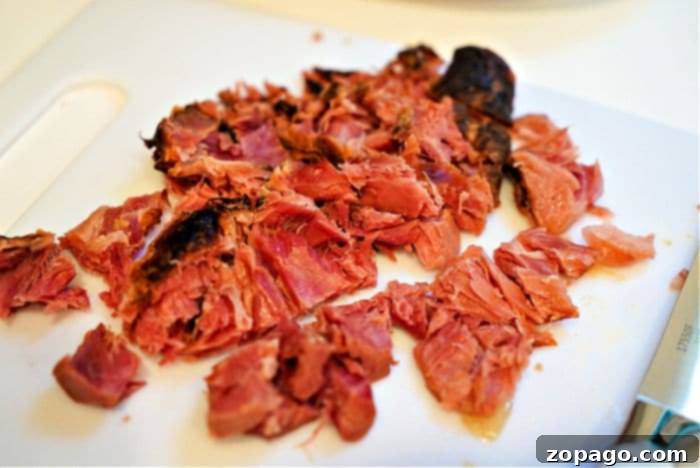 Making Mouthwatering Ham Hocks 5 Chopped smoked ham hocks on a white cutting board, reminiscent of how to cook ham hocks in a slow cooker, ready for serving.