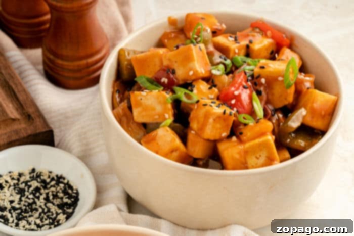 Tangy Tofu Wok Toss 6 A close-up of a sweet and sour tofu dish garnished with sesame seeds and green onions