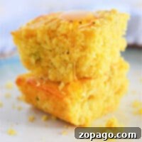 Two pieces of Jiffy Mexican Cornbread stacked, drizzled with honey on a white plate.