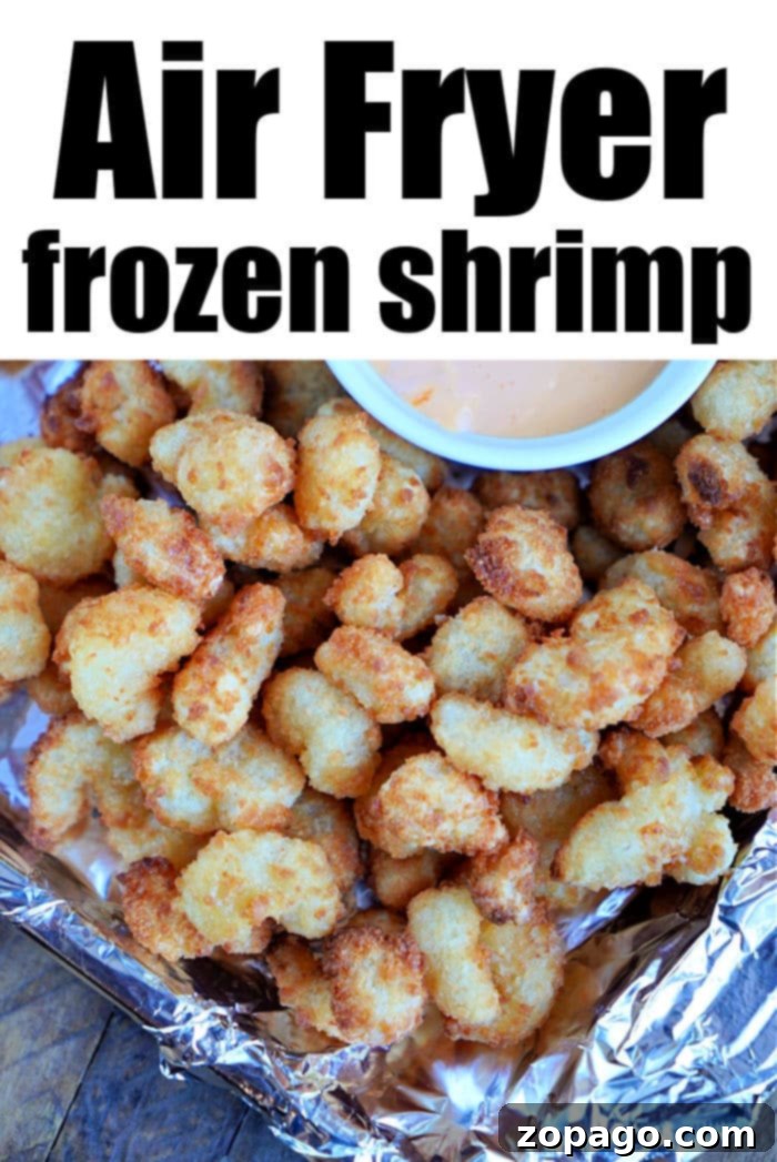 Perfectly Crispy Air Fryer Popcorn Shrimp 5 A pile of crispy frozen popcorn shrimp sits on foil, topped with a small bowl of dipping sauce. The text above reads Air Fryer frozen shrimp.