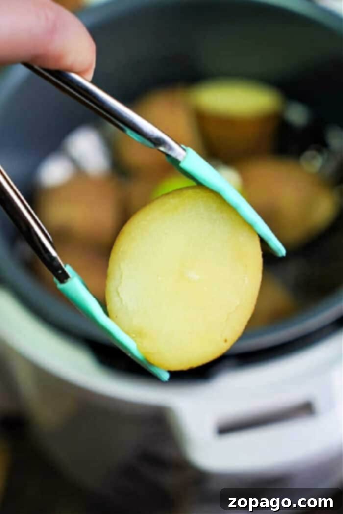 Easy Instant Pot Potatoes 2 Close-up of tongs lifting a perfectly cooked potato slice from the bubbling Instant Pot, demonstrating ideal tenderness.
