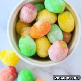 A bowl of colorful, sugar-coated grapes sits on a marble surface, resembling a delightful tutorial on how to make candied grapes with Jello.