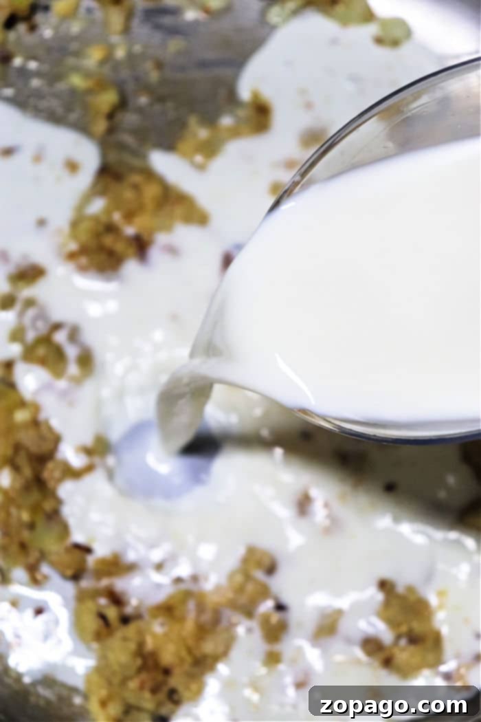 Mastering Chicken Drippings Gravy 4 Pouring milk into a mixture of smooth gravy from chicken drippings.