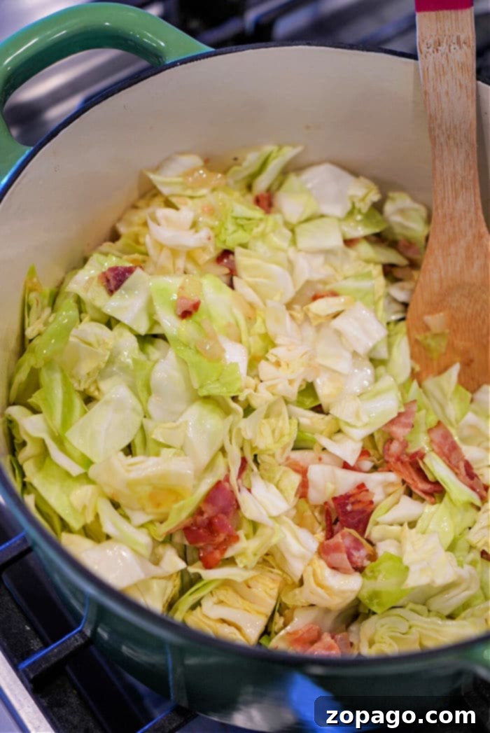 Mastering Hand-Cutting Cabbage 13 A pot brimming with sautéed swamp cabbage and crispy bacon, gently stirred with a wooden spoon.