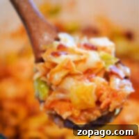 A close-up of a wooden spoon holding cooked swamp cabbage and noodles in a pot captures the essence of comfort food.