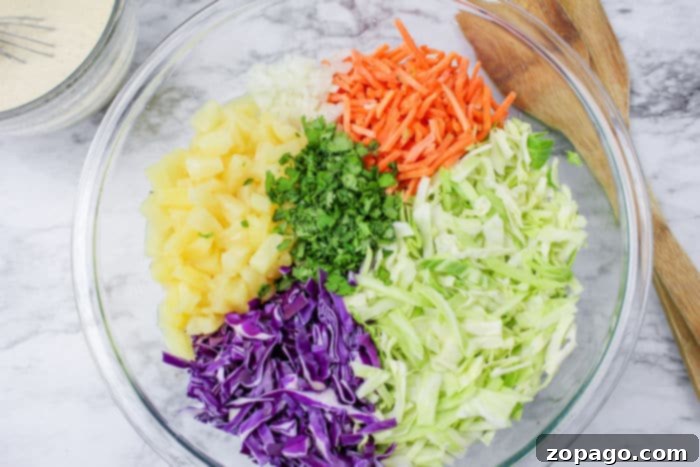 Creamy Hawaiian Pineapple Slaw 4 Close-up of vibrant pineapple coleslaw with red and green cabbage, carrots, and pineapple chunks.