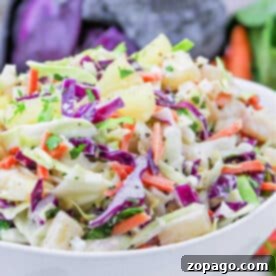 Creamy Hawaiian Pineapple Slaw 7 A bowl of colorful Hawaii Coleslaw with green and purple cabbage, carrots, pineapple, and fresh herbs.