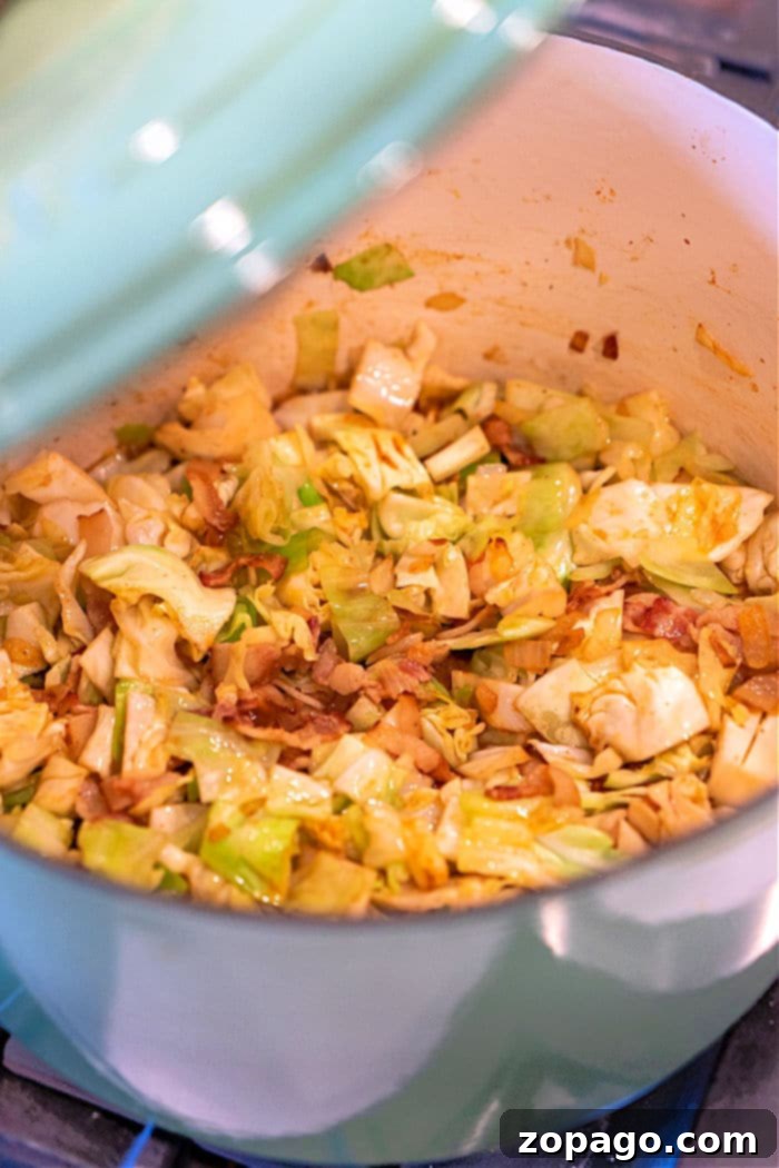Golden Southern Skillet Cabbage 6 Southern fried cabbage cooking in a Dutch Oven, showing tender cabbage and savory additions.