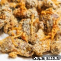 Close-up of crispy, golden brown fried gizzards with a breaded coating on a white plate, reminiscent of perfectly cooked air fryer chicken gizzards.
