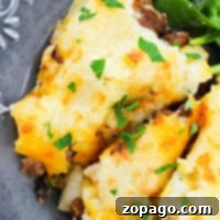 Streamlined Shepherds Pie with Instant Potatoes 6 Shepherds pie with instant potatoes, crowned with golden mashed perfection and garnished with parsley, rests on a decorative plate beside fresh greens.