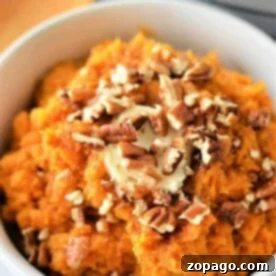 Instant Pot Sweet Mashed Potatoes topped with chopped pecans and a pat of butter in a white bowl.