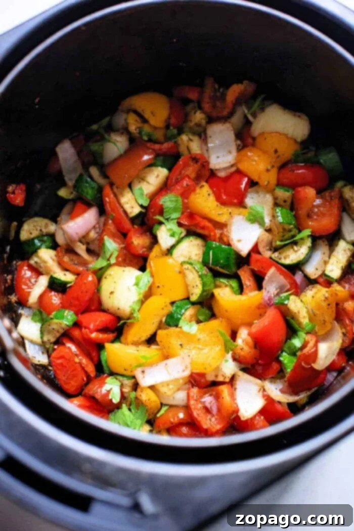 Perfect Air Fryer Mediterranean Roasted Vegetables 2 Air fryer basket filled with vibrant chopped vegetables like peppers, onions, and zucchini, ready to be roasted in Mediterranean style for a healthy meal.