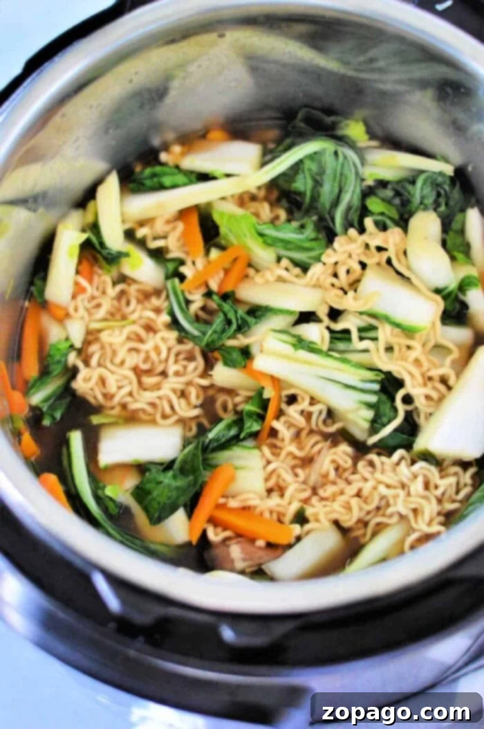 Perfect Instant Pot Ramen 7 A top-down view of ramen noodles and mixed vegetables simmering in a savory broth inside an Instant Pot, highlighting the ease and speed of cooking a delicious meal.