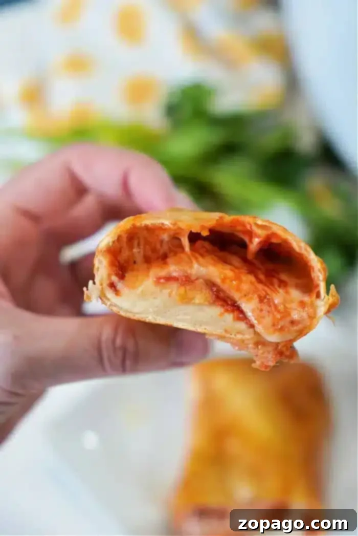 No More Cold Spots Hot Pocket Cook Time Secrets 2 A hand holding half of a stuffed, golden-brown baked tortilla, with melted cheese and a tomato filling visible.