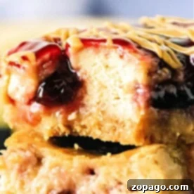 Close-up of a decadent Peanut Butter and Jelly Cheesecake Bar with a bite taken out, revealing its luscious layers of filling and topping.