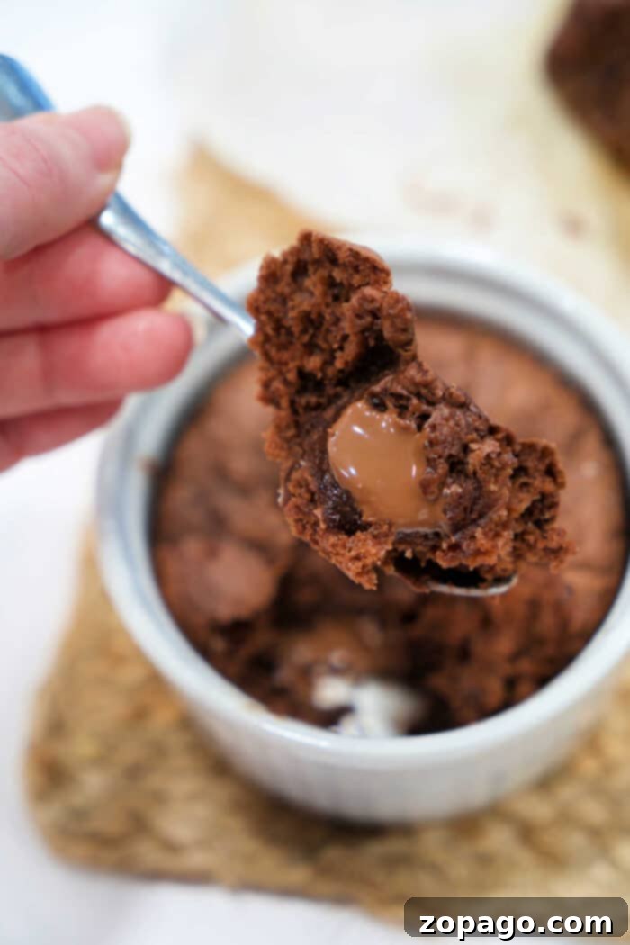 Mug Lava Cake Magic 2 Delicious chocolate lava cake in a ramekin with a spoonful taken out, showing the molten chocolate center.