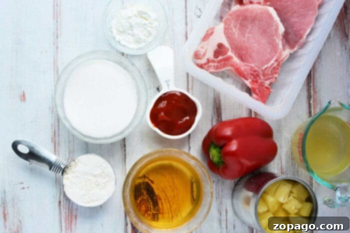 Raw pork chops, red bell pepper, flour, sugar, ketchup, pineapple, broth, and cornstarch sit on a white surface—ideal ingredients for delicious Pork Chop Recipes.