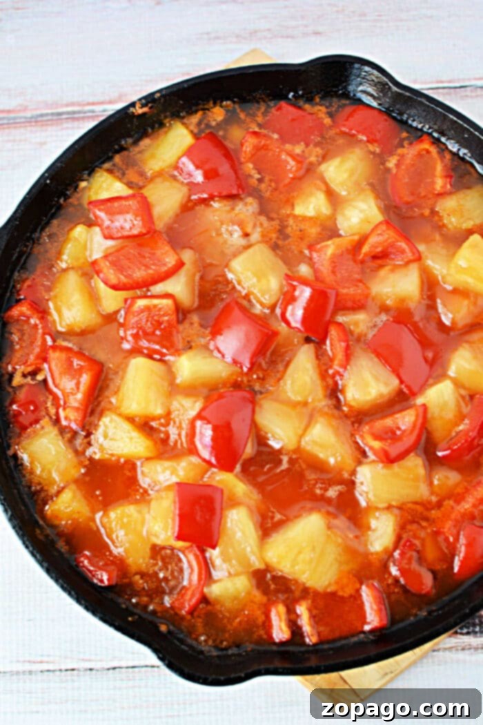A skillet filled with sweet and sour sauce, pineapple chunks, red bell peppers, and tender pork chops—perfect for trying new pork chop recipes.
