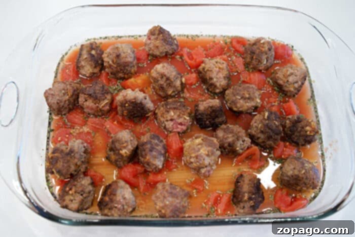 Cheesy Baked Spaghetti Meatball Bake 7 Baking dish with meatballs, diced tomatoes, sauce, and herbs, arranged over uncooked lasagna noodles for a delicious twist on Baked Spaghetti with Meatballs.