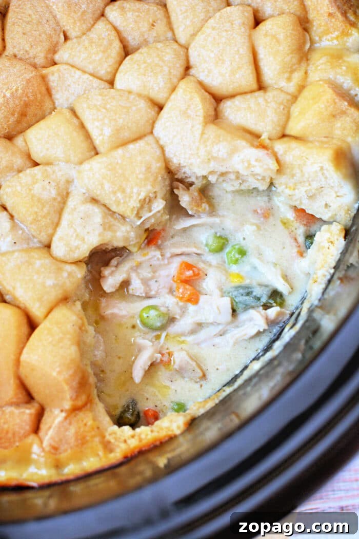 Slow-Cooker Chicken Pot Pie: Creamy One-Pot Dinner Recipe 2 Close-up of a creamy Chicken Pot Pie with vegetables and a golden-brown biscuit topping, partially served—comfort food made easy in the Crockpot.