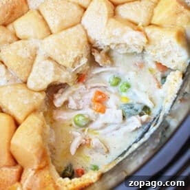 Slow-Cooker Chicken Pot Pie: Creamy One-Pot Dinner Recipe 8 Close-up of a creamy Chicken Pot Pie with vegetables and a golden-brown biscuit topping, partially served—comfort food made easy in the Crockpot.