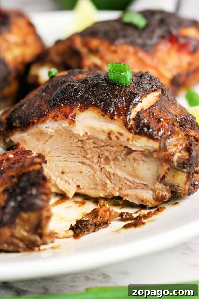 Oven-Baked Jerk Chicken Recipe with Crispy Skin and Spicy Glaze 2 A close-up of juicy, oven jerk chicken with crispy, seasoned skin, garnished with chopped green onions.