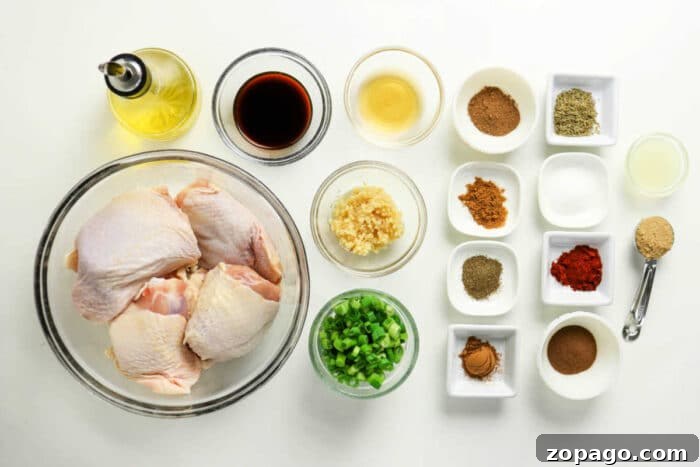 Oven-Baked Jerk Chicken Recipe with Crispy Skin and Spicy Glaze 3 Raw chicken thighs, chopped green onions, minced garlic, sauces, oil, and various spices arranged on a white surface—perfect for preparing flavorful Oven Jerk Chicken.