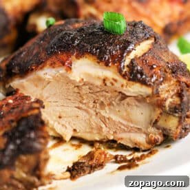 Oven-Baked Jerk Chicken Recipe with Crispy Skin and Spicy Glaze 7 A close-up of juicy, oven jerk chicken with crispy, seasoned skin, garnished with chopped green onions.