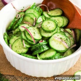 Cucumber and Dill Salad with Creamy Yogurt Dressing 7 Bowl of cucumber salad with crisp red onion slices and fresh dill, all mixed together with a wooden spoon.