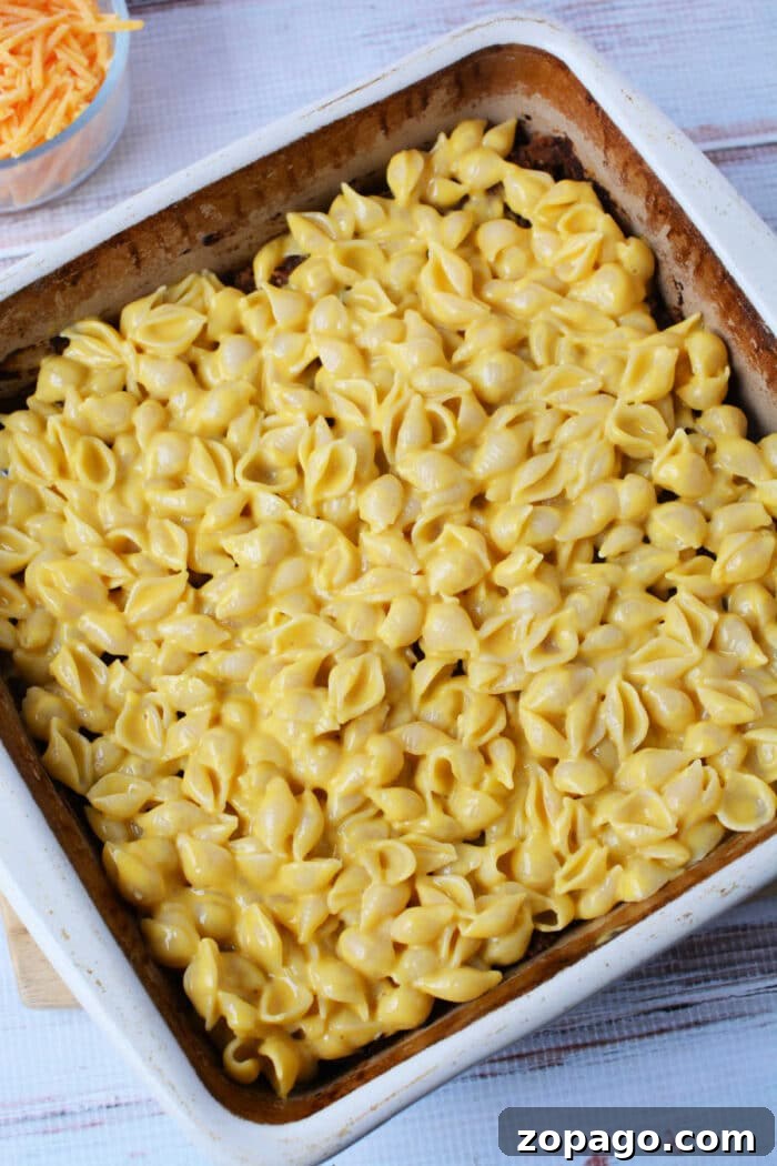 Mac and Cheese Meatloaf Casserole Bake 5 A baking dish filled with creamy mac and cheese made with shell pasta, ready to be baked into a delicious casserole.