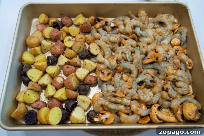 Garlic Butter Shrimp with Crispy Roasted Potatoes 5 Sheet pan with seasoned baby potatoes on the left and raw shrimp and mushrooms on the right, this shrimp and potatoes combo is ready to bake.